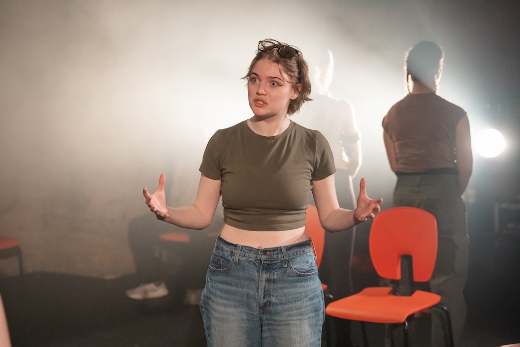 Action shot of the spring 2024 Shakespeare in Performance at RADA final presentation of Julius Caesar. An actor stands in mid-performance with her arms outstretched and an intense expression on her face.